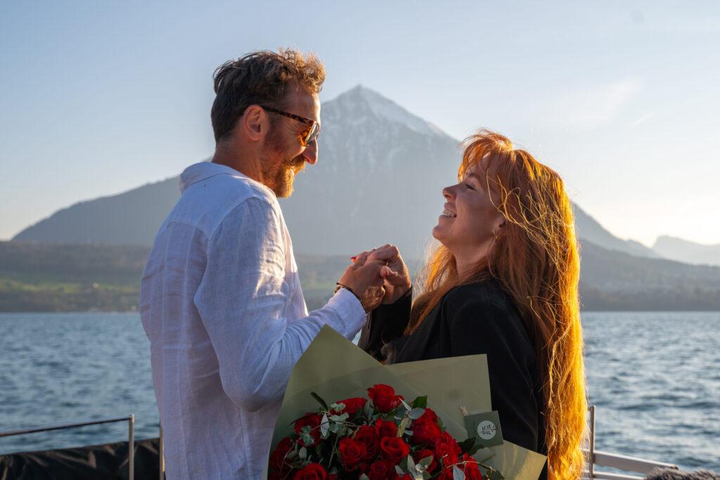 Romantic moment after boat engagement with red roses on Lake Thun
