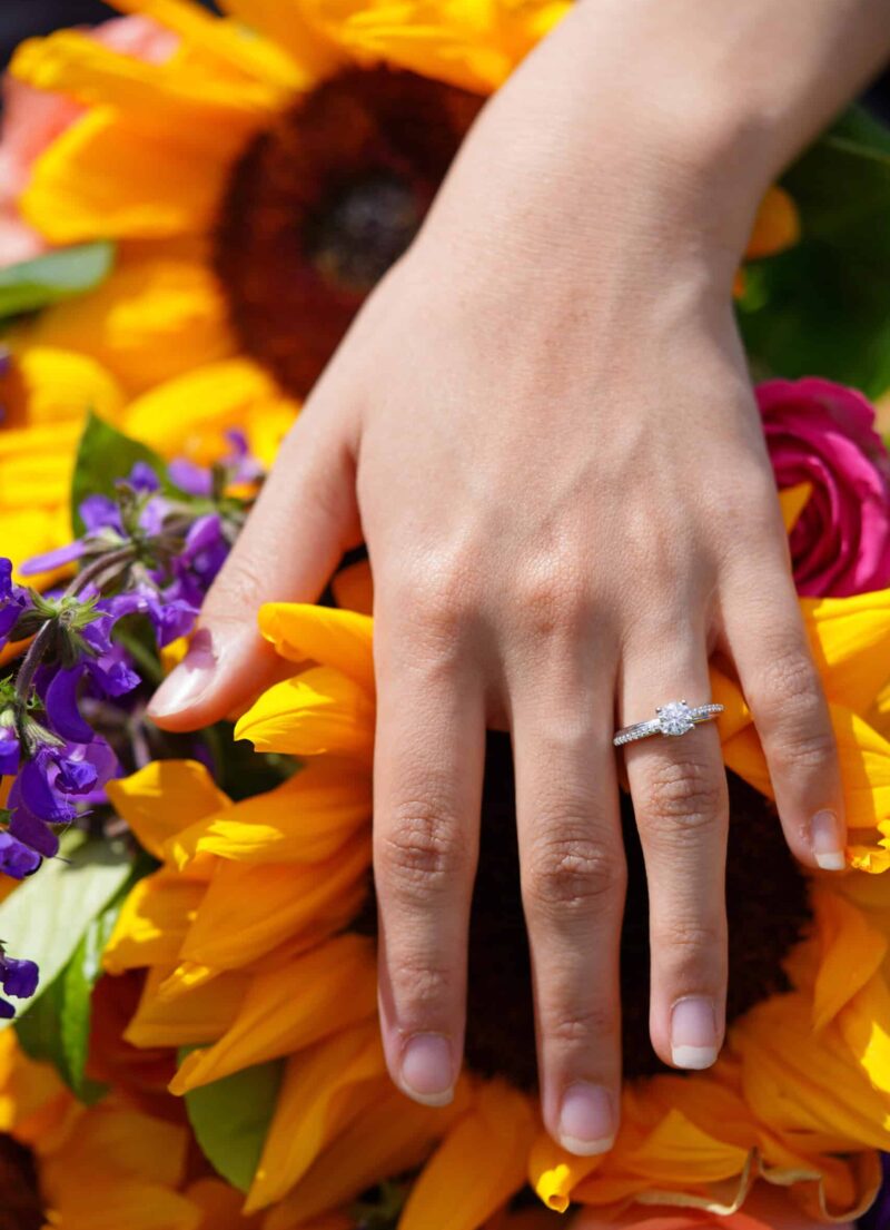Close-up of engagement ring on hand resting on local wildflowers during a Swiss picnic proposal