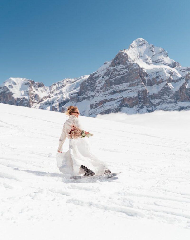 Bride snowboarding at First, Grindelwald – winter ski elopement in the Swiss Alps