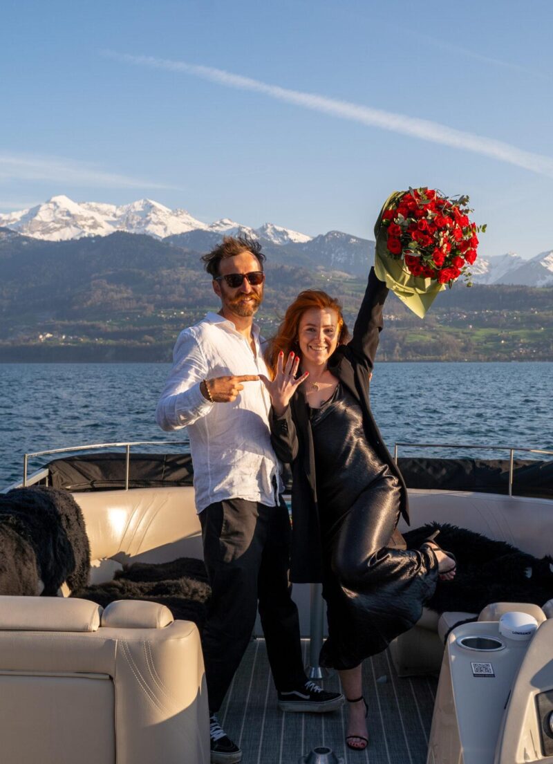 Private boat proposal on Lake Thun with red rose bouquet and champagne