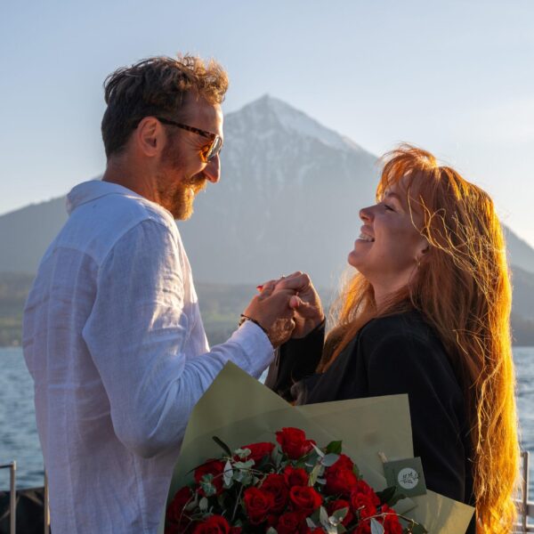 Romantic moment after boat engagement with red roses on Lake Thun